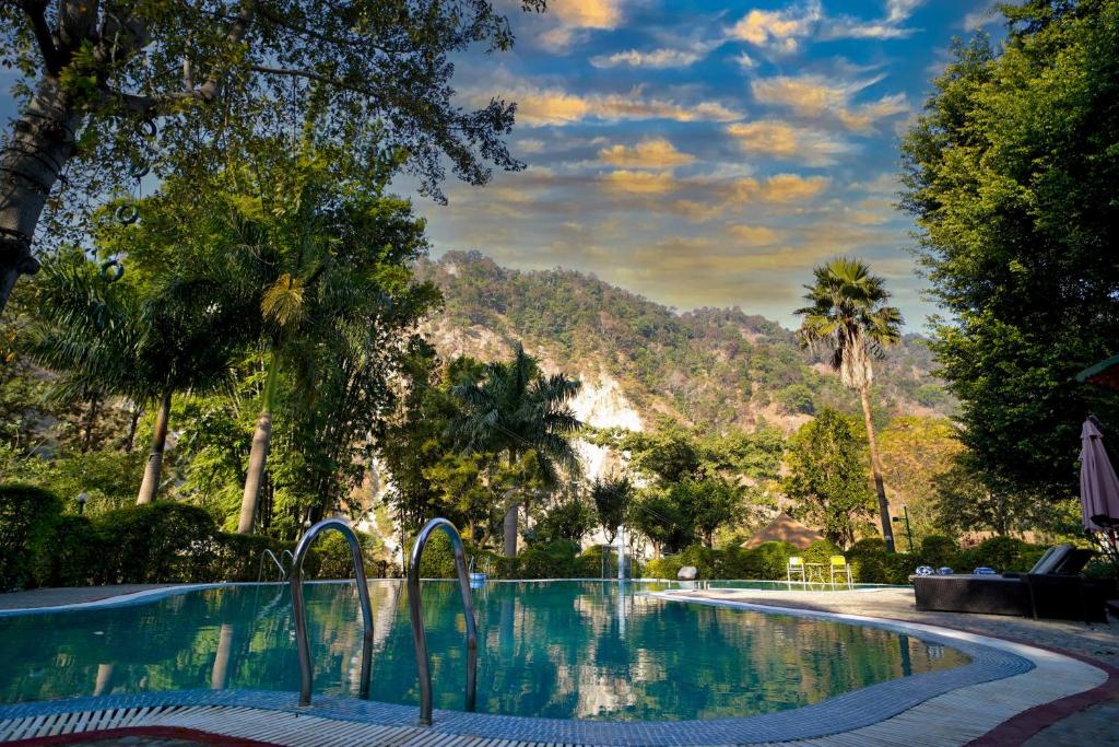 una piscina con árboles y una montaña en el fondo en The Solluna Resort, en Garjia