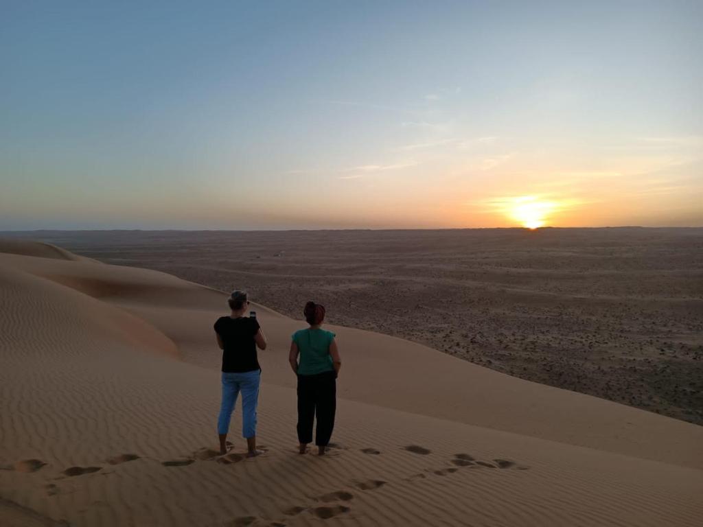 two people standing in the desert watching the sunset at Moon Light Camp in Bidiyah