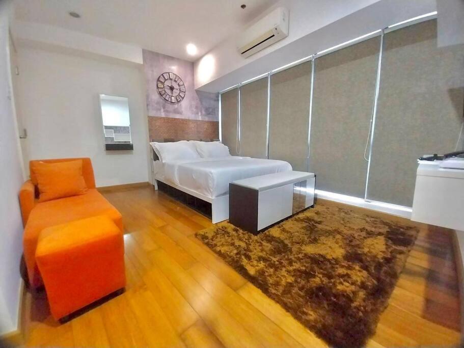 1 dormitorio con 1 cama, 1 silla y 1 reloj en Modern-Eclectic 1BR- Unit @Milano, en Manila