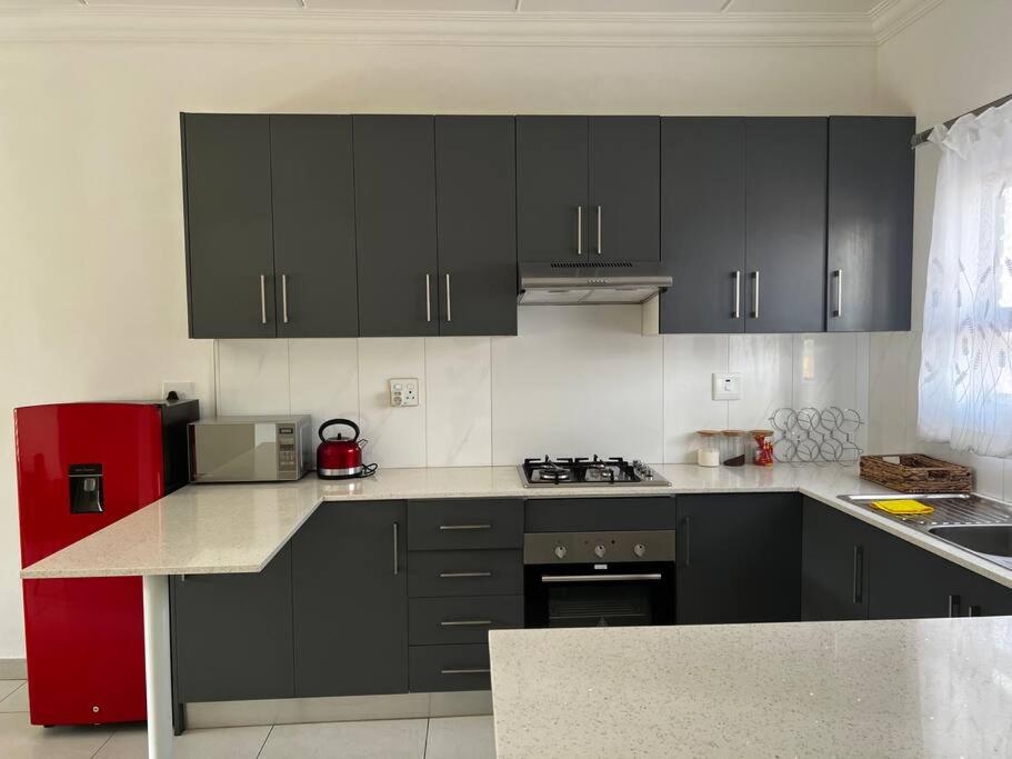 a kitchen with black cabinets and a red refrigerator at PebetzeLuxuryHomes Near OR TAMBO AIRPORT in Boksburg