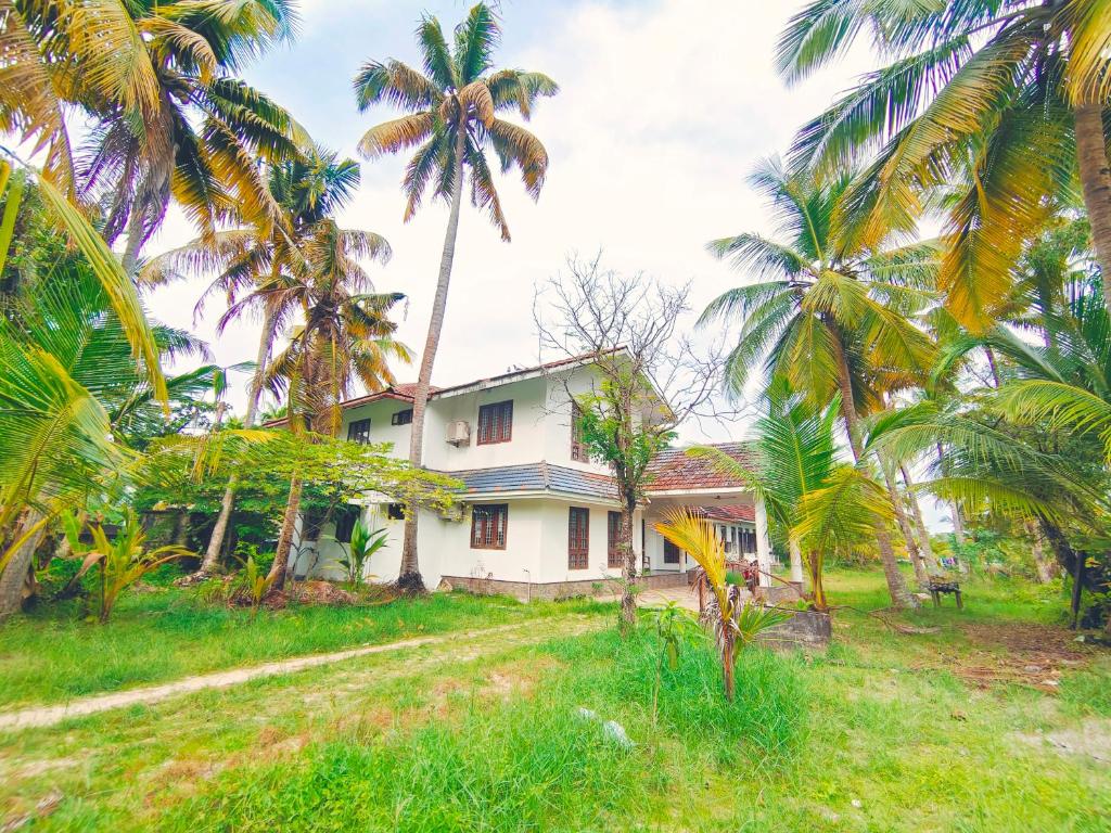 uma casa velha com palmeiras em frente em White Sands Homestay em Turavūr