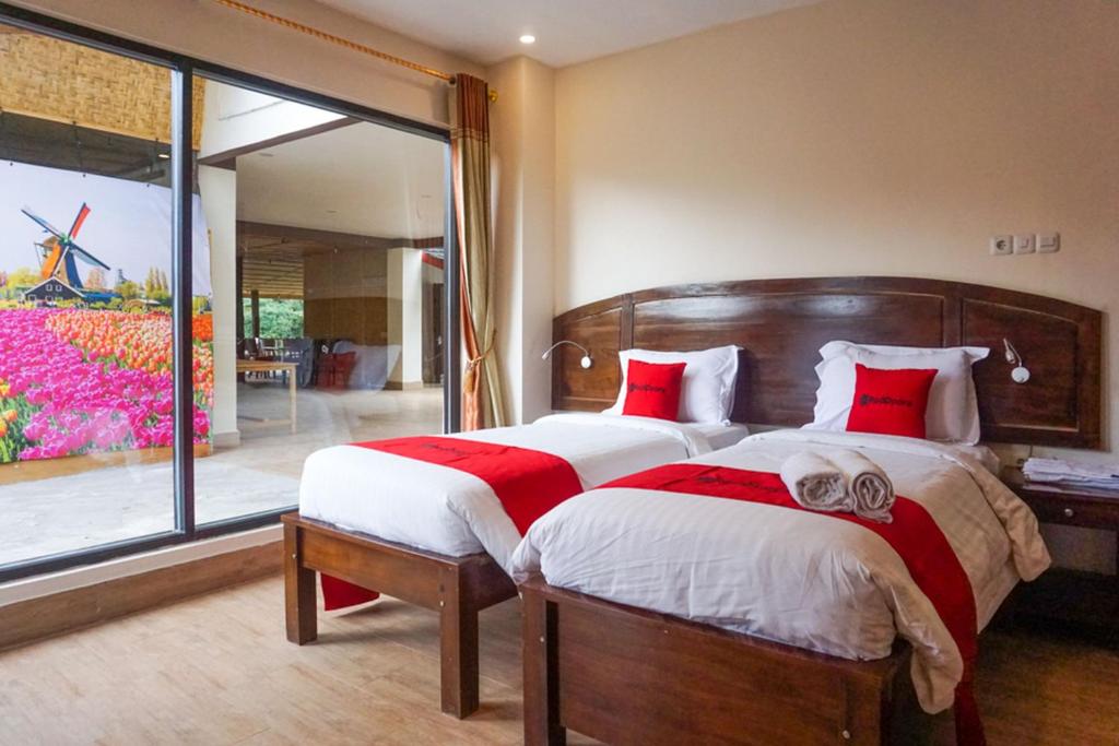 a bedroom with a large bed with red and white pillows at RedDoorz near Londa Toraja in Madandan