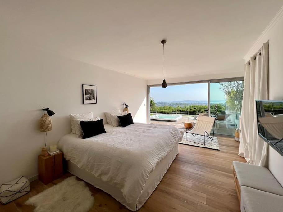 une chambre avec un grand lit et une grande fenêtre dans l'établissement Maison d'artiste Vue mer & Jacuzzi, à Vallauris