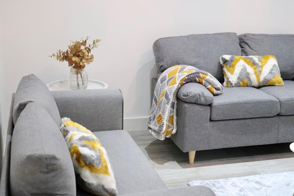 a living room with a gray couch and a table at Contemporary & Stylish House . FREE Parking in Beeston Hill