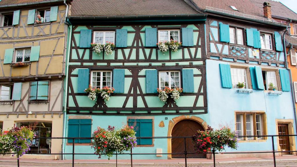 an old house with blue shutters and flowers in front of it at Dock 23 in Colmar