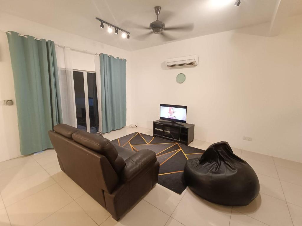 a living room with a couch and a television at Elvy Homestay Alam Sutera Puncak Alam in Bandar Puncak Alam