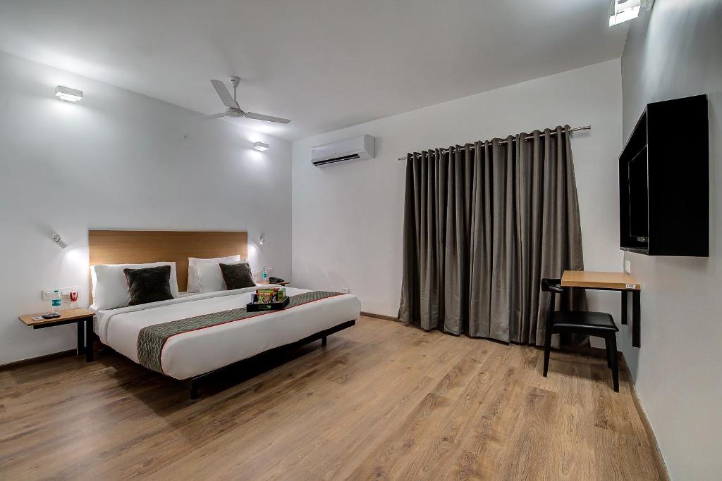 een slaapkamer met een bed, een televisie en een bureau bij Townhouse 056 T Nagar Chennai Near AGS Cinemas T Nagar in Chennai