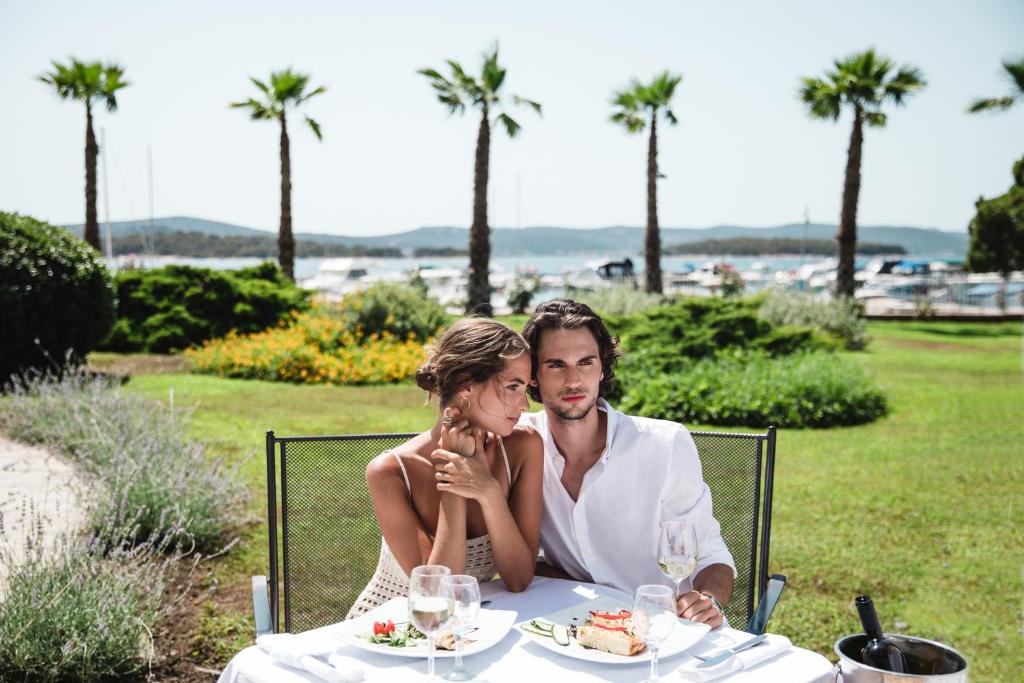 a bride and groom sitting at a table with food at Hotel Ilirija in Biograd na Moru