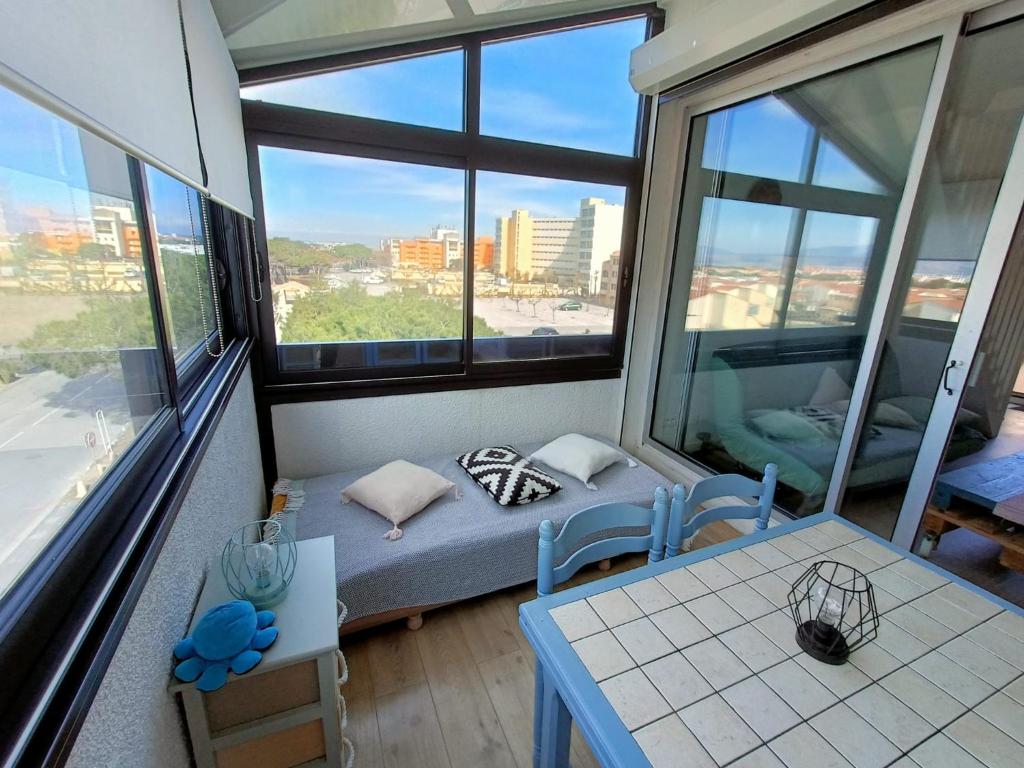 Habitación con 1 cama, 2 mesas y ventanas en L'appart de Fanch, en Le Barcarès