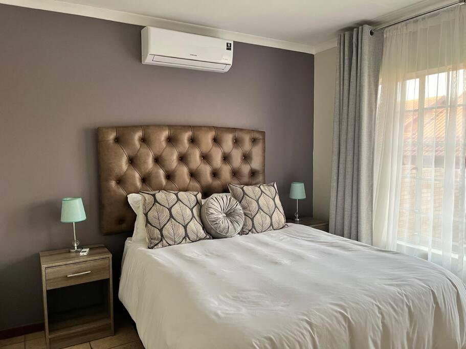 a bedroom with a large bed with white sheets and pillows at The Reeds: 2 Bedroom townhouse in Centurion