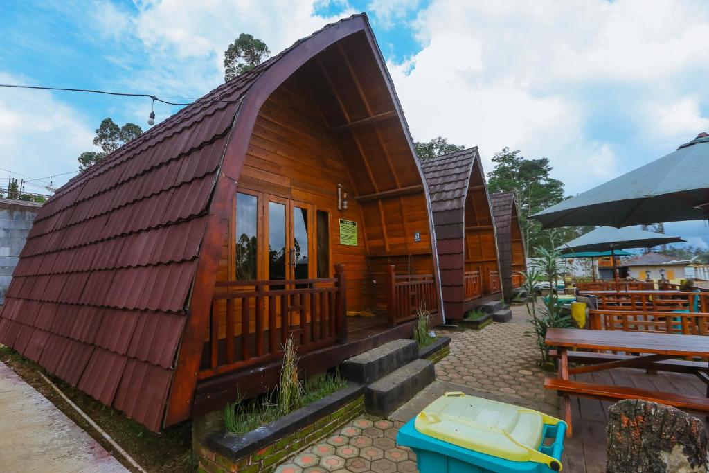 a small wooden house with a bench and a table at De Bloem Lake View Pangalengan in Pengalengan