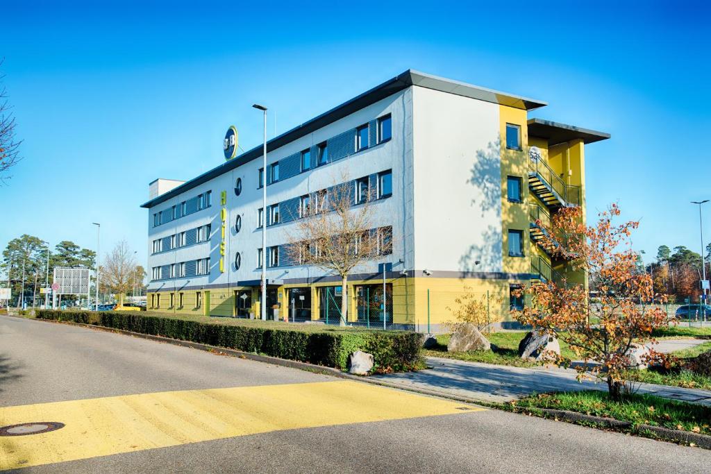 B&B HOTEL Baden-Airpark في Rheinmunster: مبنى ابيض واصفر على جانب شارع