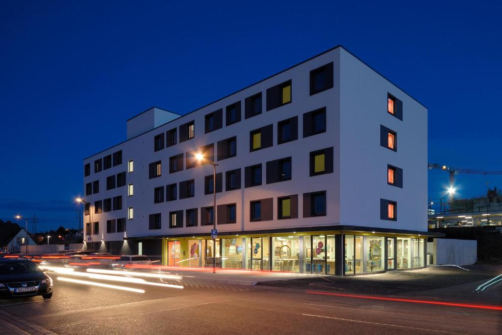 ein weißes Gebäude mit einem davor geparkt in der Unterkunft B&B Hotel Böblingen in Böblingen