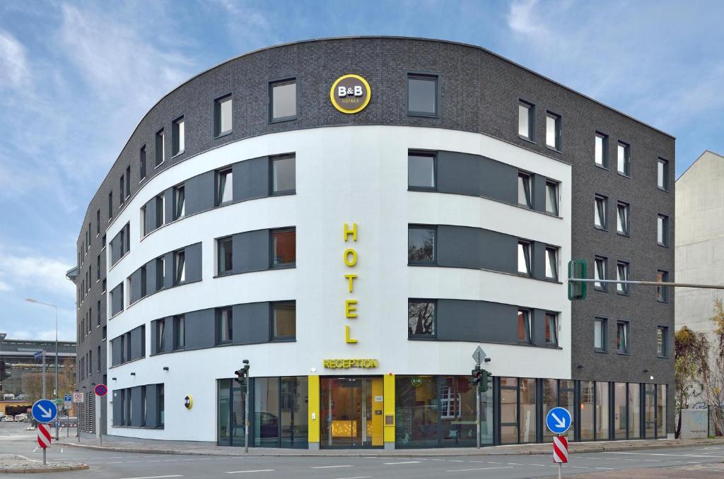 a large white building with a yellow sign on it at B&B HOTEL Erfurt-Hbf in Erfurt