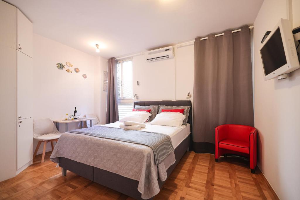 a bedroom with a bed and a red chair at Sea Organ Apartment 2 (Oldtown Studio) in Zadar