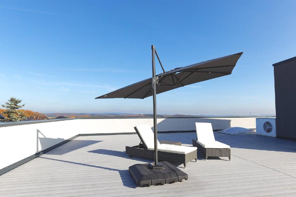 eine Terrasse mit zwei Stühlen und einem Sonnenschirm auf einer Terrasse in der Unterkunft Apartments Panoramablick in Mettlach