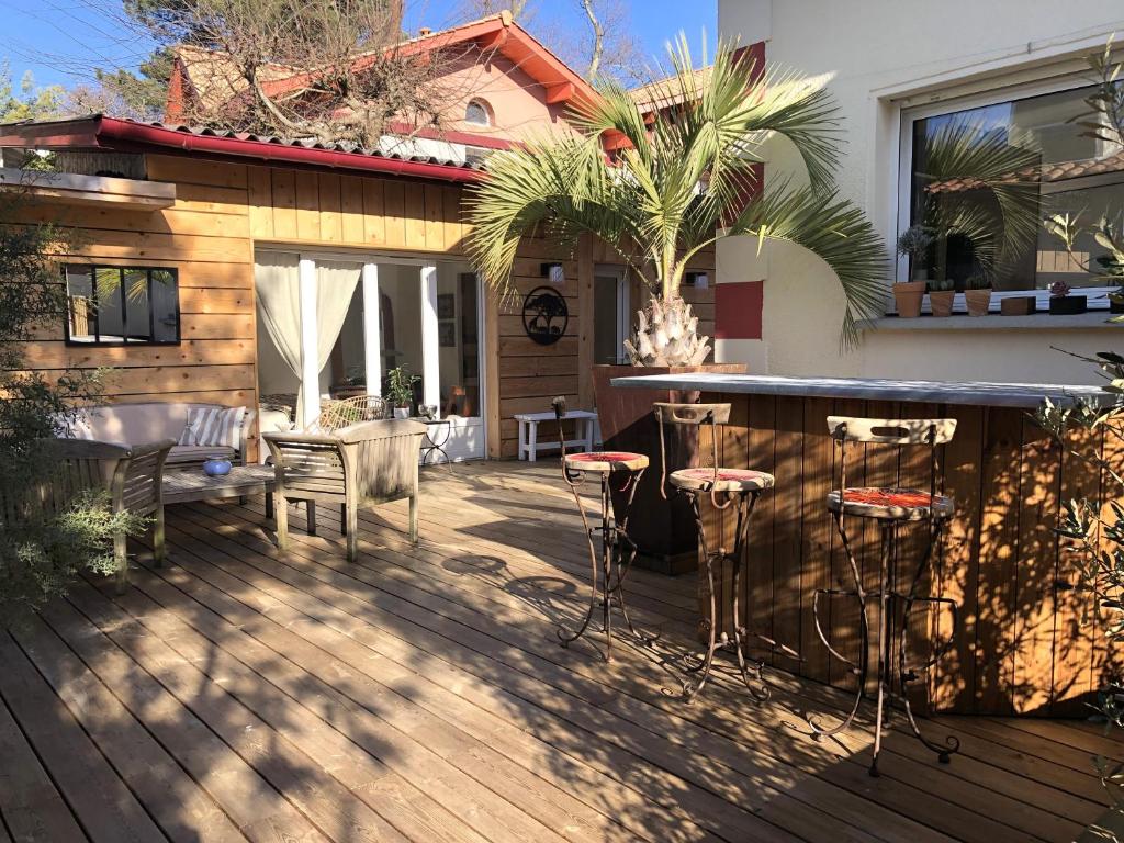 un patio con bar y taburetes en una terraza en FLEUR DES PINS Maison tout confort au calme, en Arcachon