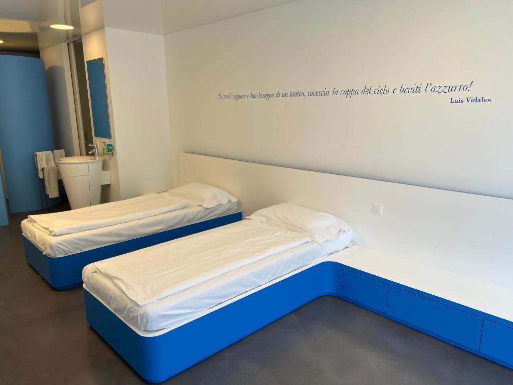 two beds in a hospital room with a sign on the wall at Chromotel self check-in in Mezzovico