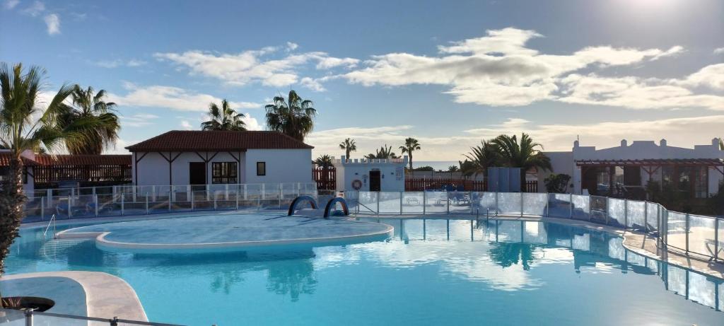 a large swimming pool in a resort with palm trees at Casa SolyMar Canarias 6 in Caleta De Fuste