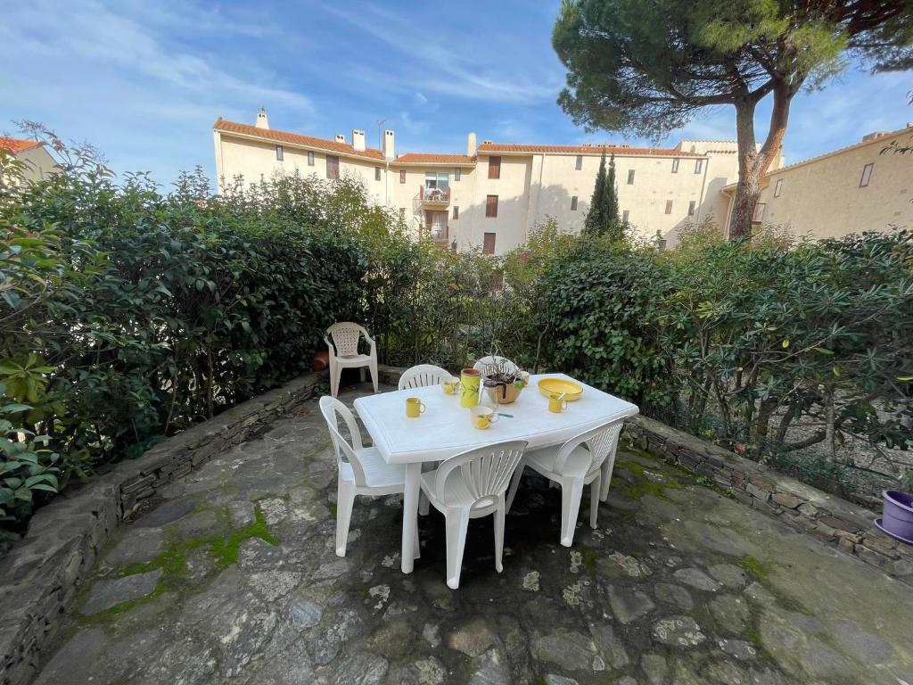 une table blanche et des chaises assises sur une terrasse dans l'établissement 4VSE-ALZ10 Résidence Val Saint-Elme, à Collioure