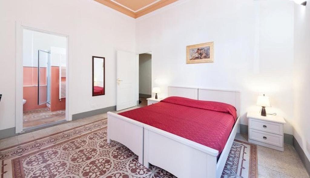 Dormitorio blanco con cama roja y espejo en Guest House L'Aranceto, en Florencia