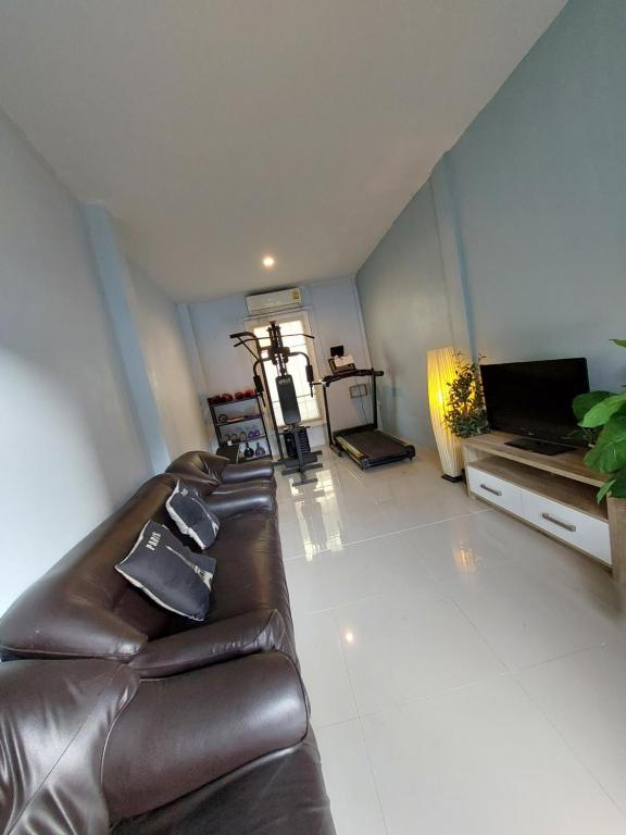 ein Wohnzimmer mit einem Ledersofa und einem TV in der Unterkunft Mercy Hostel in Chiang Rai