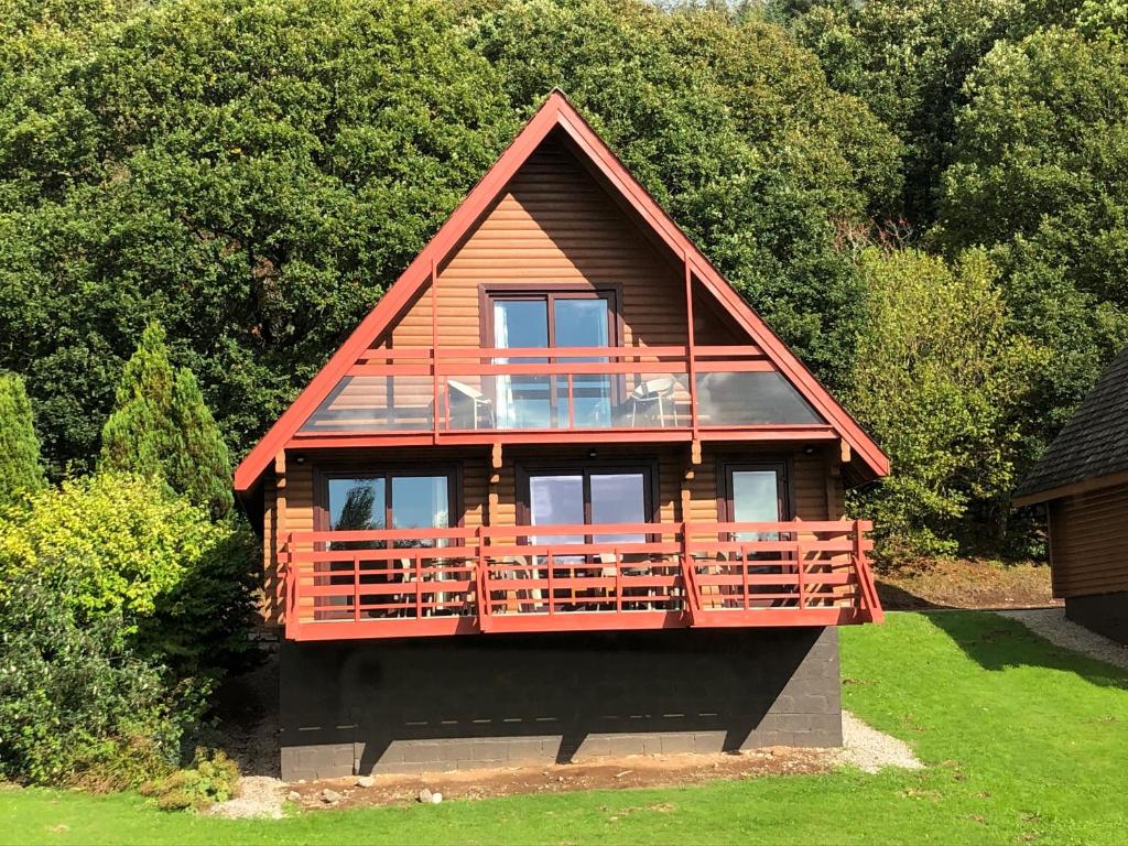 a house with a large deck in the grass at Thistle Lodges at Sandyhills Bay in Dalbeattie
