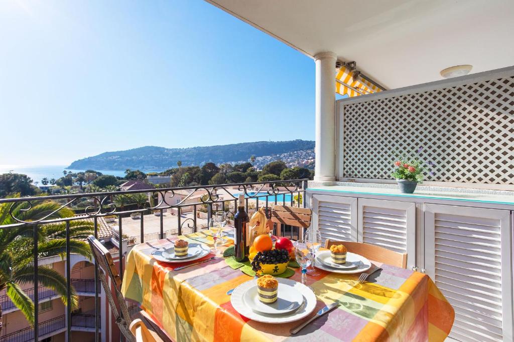 a table on a balcony with a view of the ocean at Ange Gardien IV AP4326 By Riviera Holiday Homes in Villefranche-sur-Mer