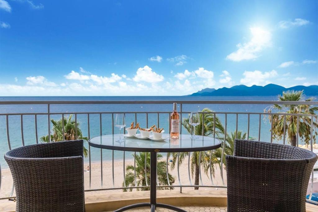 - une table avec une bouteille de vin et 2 chaises dans l'établissement PLAGE Superb bright apartment with sea view & close to Cannes center, à Cannes