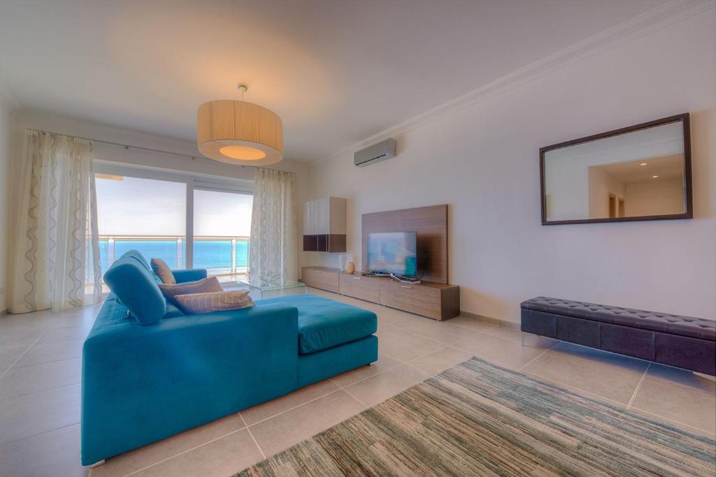 ein Wohnzimmer mit einem blauen Sofa und einem TV in der Unterkunft Seafront Luxury Apartment with Pool in Sliema