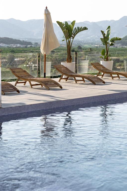 a pool with benches and an umbrella next to the water at Finca de l’Anglés. Levante in Potríes