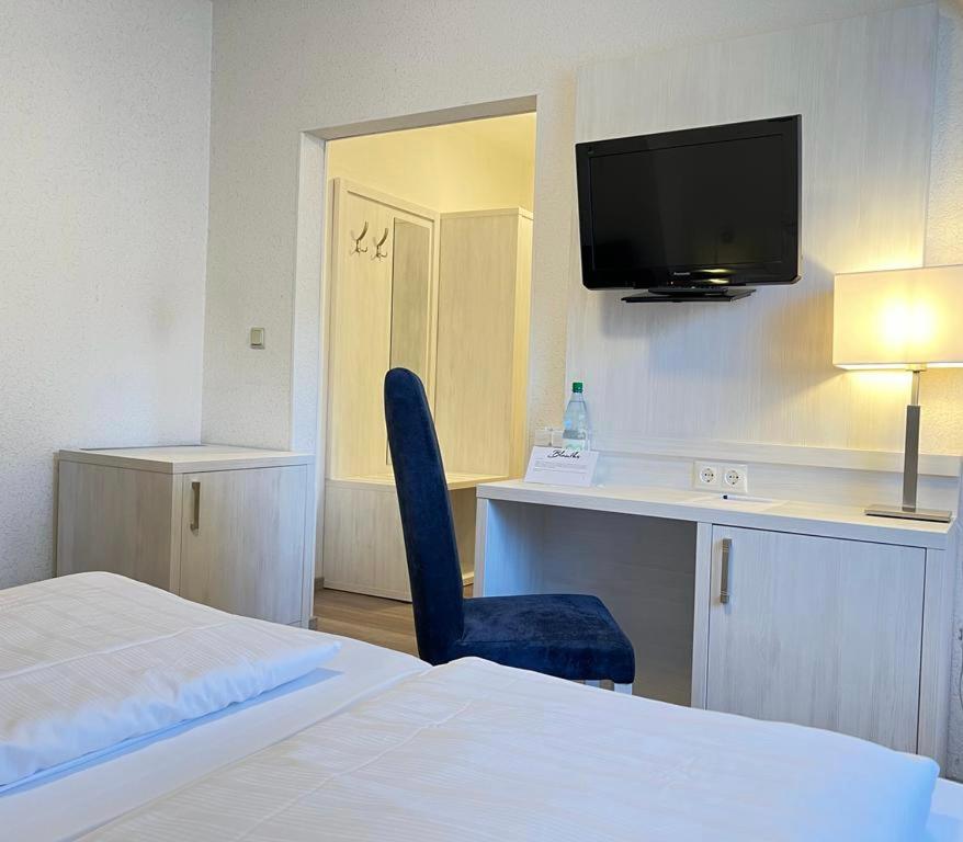 a hotel room with a bed and a desk and a tv at Haus zur Heimat in Cuxhaven