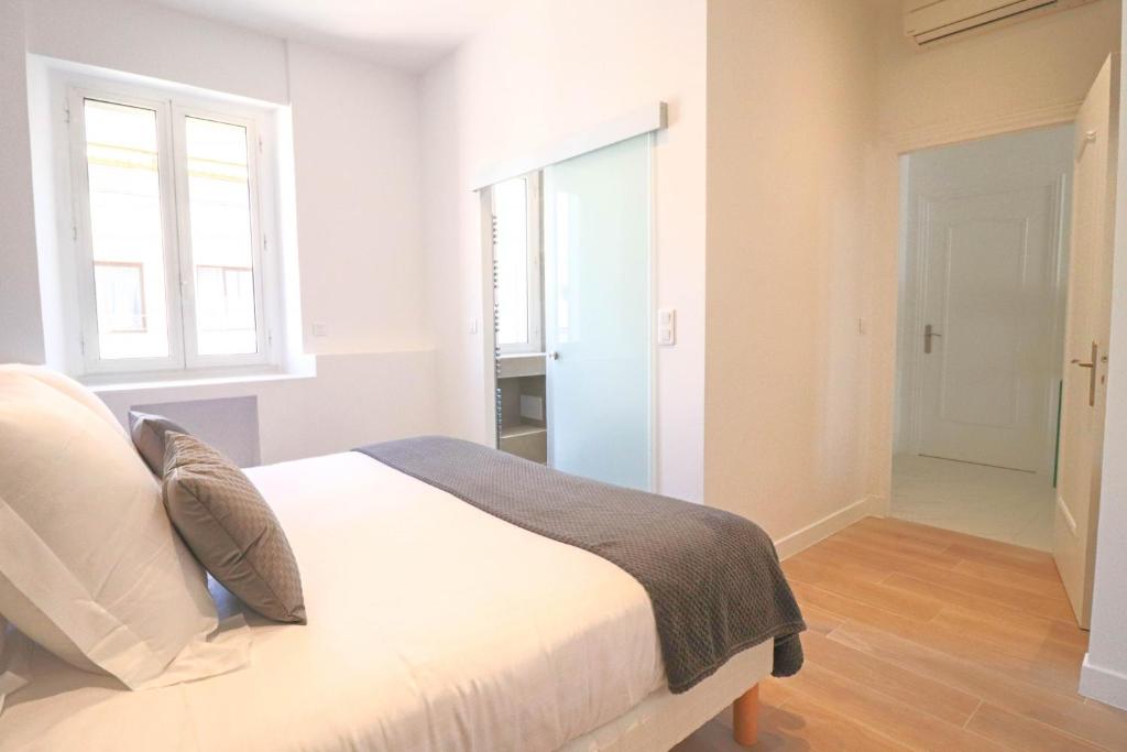 a white bedroom with a bed and a window at NAPOLEON Luxurious renovated apartment 1min from Palais in Cannes