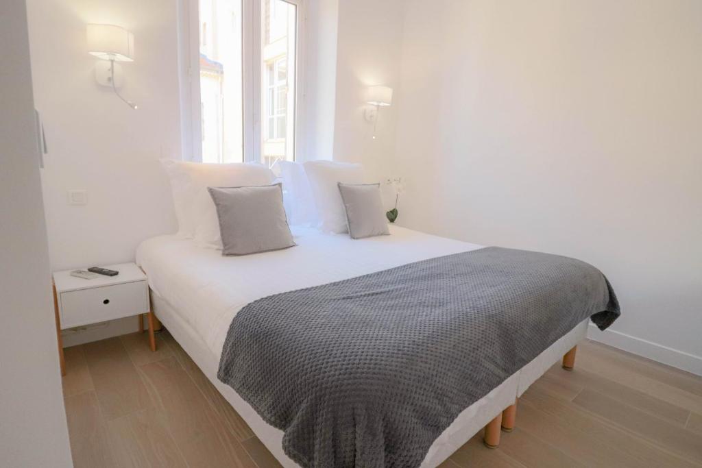 a bedroom with a white bed with pillows at NAPOLEON Luxurious renovated apartment 1min from Palais in Cannes