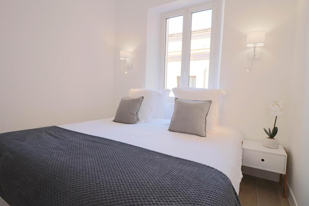 a bedroom with a white bed with two pillows at NAPOLEON Luxurious renovated apartment 1min from Palais in Cannes