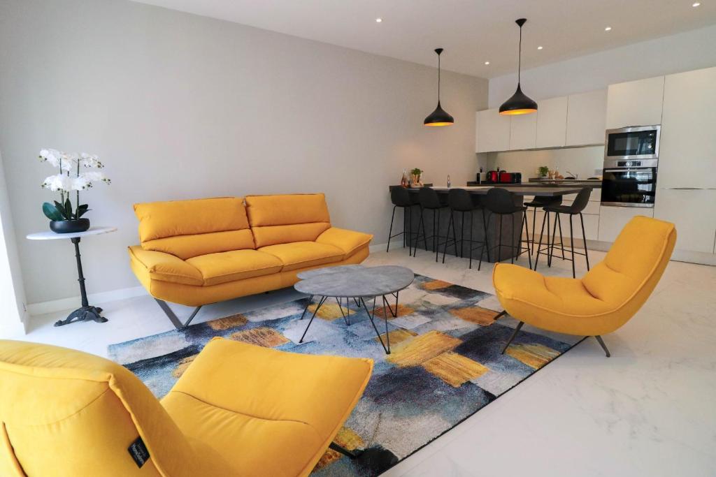 a living room with yellow furniture and a kitchen at NAPOLEON Luxurious renovated apartment 1min from Palais in Cannes