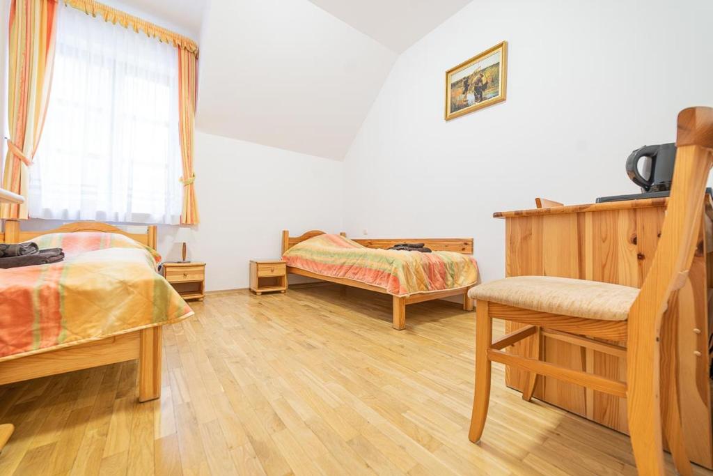 1 dormitorio con 2 camas, silla y ventana en Ośrodek Wrzosowa Góra - pokoje, en Ruciane-Nida