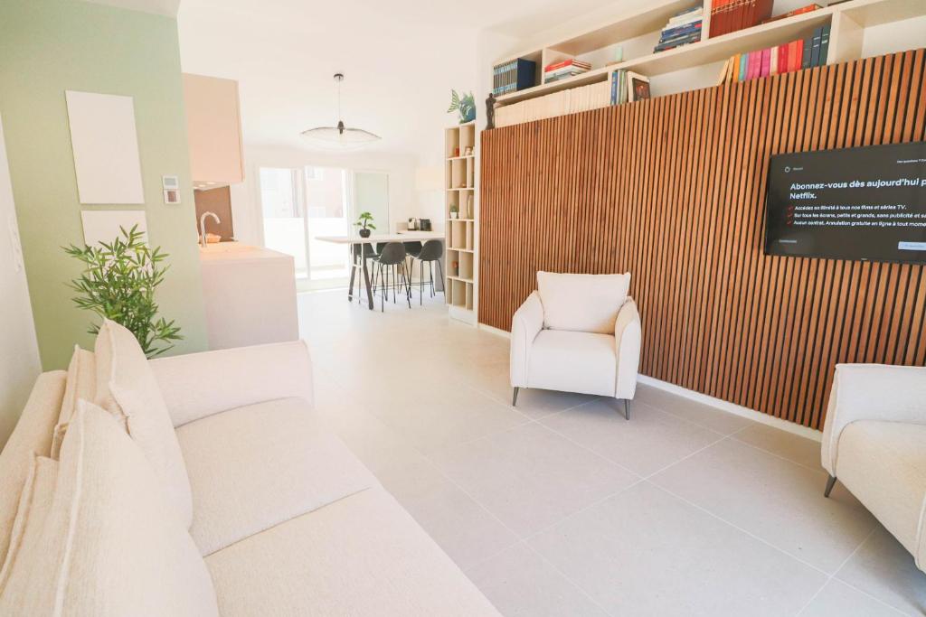 un salon avec des chaises blanches et un mur dans l'établissement MEYNADIER Renovated designer apartment with rooftop in Cannes, à Cannes