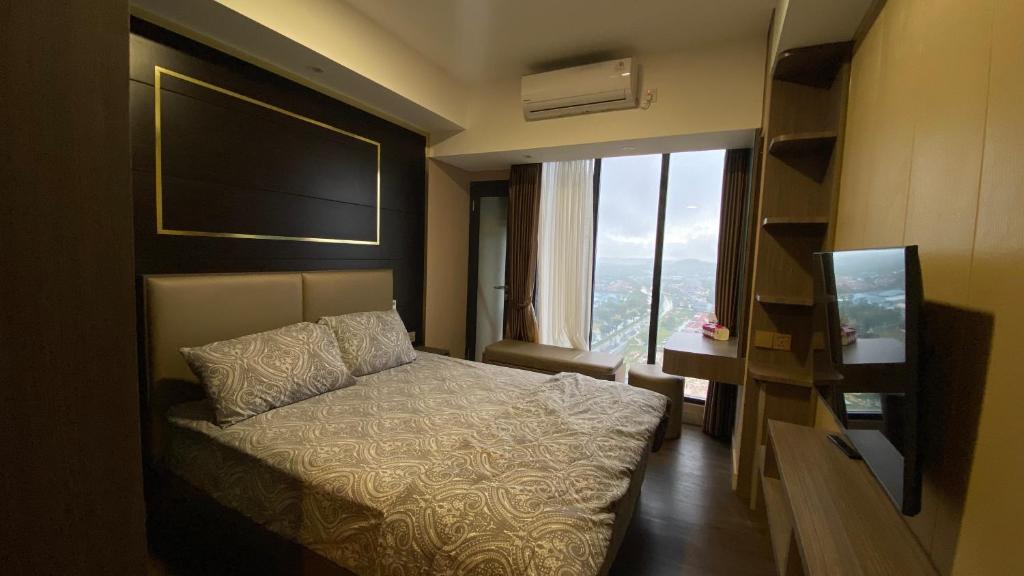 a hotel room with a bed and a large window at Meisterstadt Pollux Habibie Apartment by uhomeid in Batam Center