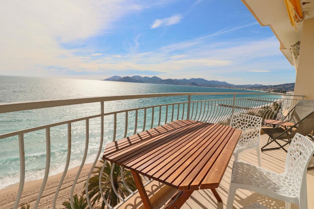 - un balcon avec une table et des chaises en bois et l'océan dans l'établissement ROOFTOP DE LA PLAGE Charming apartment on seafront with superb roof terrace, à Cannes