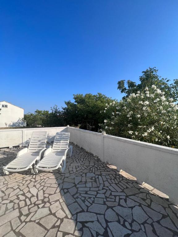 a group of white lounge chairs sitting on a patio at Apartment Tea in Rab