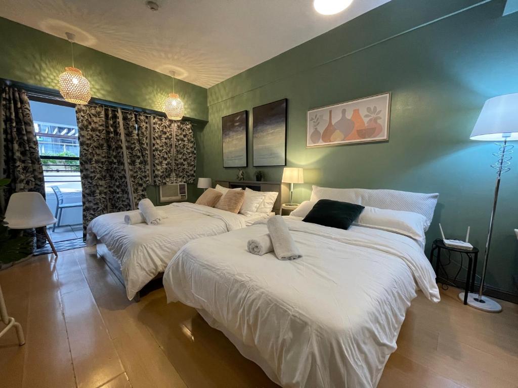 2 camas en una habitación con paredes verdes en Poolside Family Room Greenbelt Makati en Manila