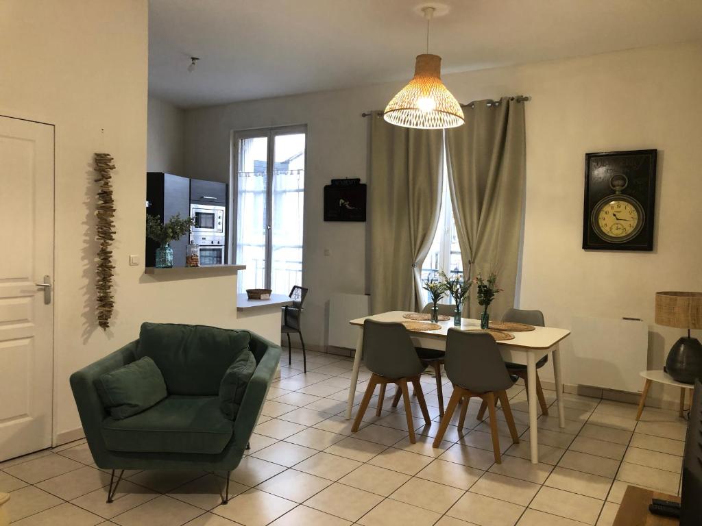 a living room with a table and a green chair at Bel appartement spacieux et lumineux hyper centre Blois in Blois