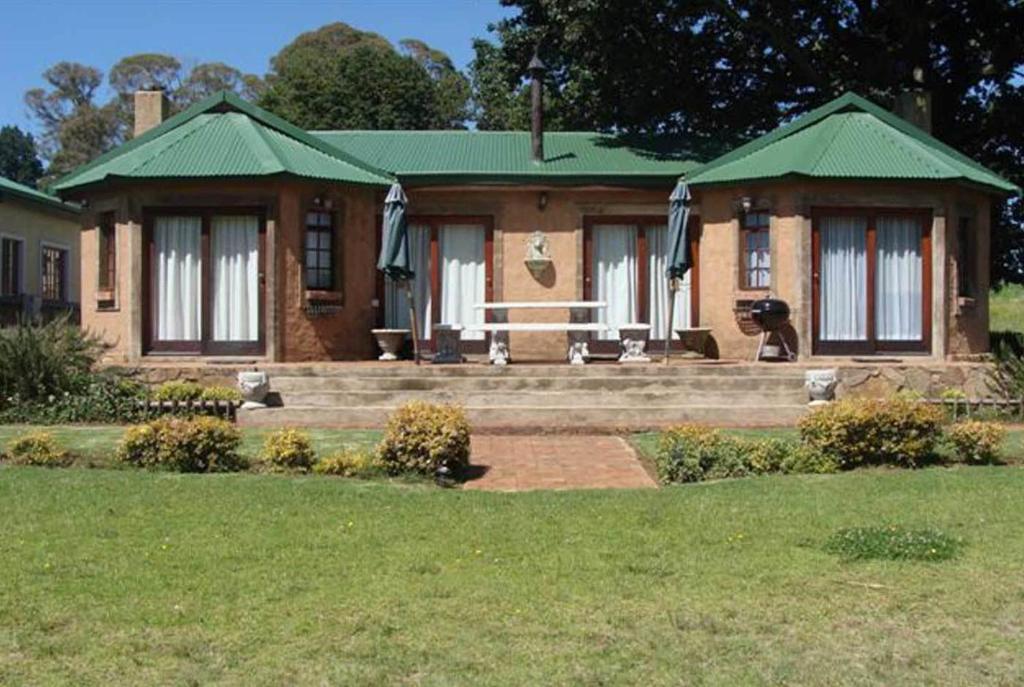 a house with a green roof and a yard at Fox & Squirrel in Dullstroom