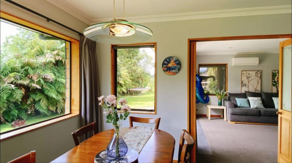 uma sala de jantar com um vaso de flores sobre uma mesa em Tranquil Stream Villa em Rotorua