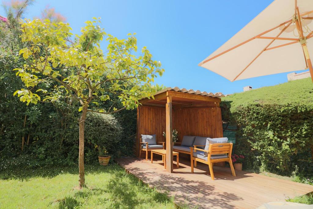 アンティーブにあるSUQUETTE Charming provencal house in Antibes with nice terrace, garden and pool accessの木製デッキ(テーブル、傘付)