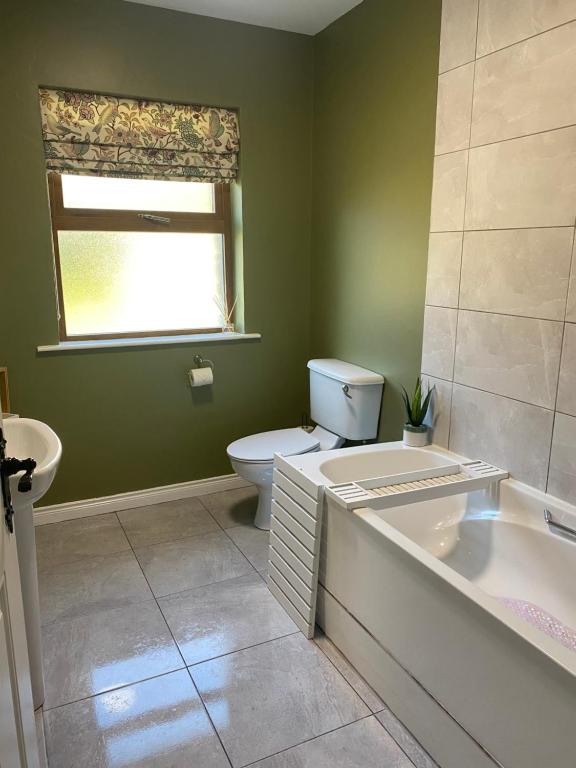 a bathroom with a tub and a toilet and a sink at Glengesh Court. Ardara town centre. in Ardara