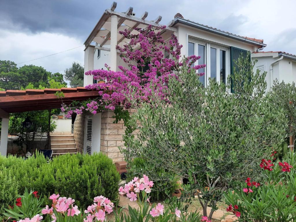 una casa con fiori rosa di fronte di Apartment Tanja a Supetar (San Pietro di Brazza)