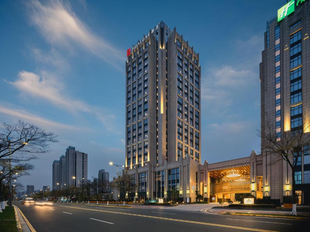 un grand bâtiment sur une rue de la ville la nuit dans l'établissement HUALUXE Kunshan Huaqiao, an IHG Hotel - F1 Racing Preferred Hotel, à Kunshan