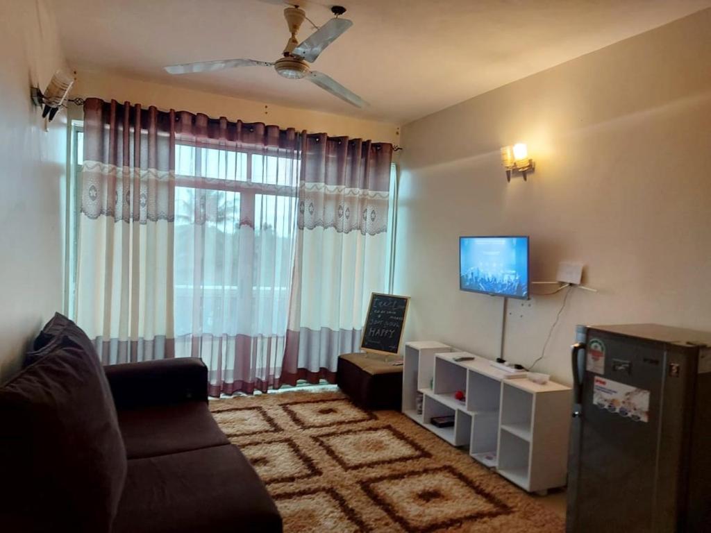 a living room with a couch and a flat screen tv at Shanzu Mombasa One Bedroom & Swimming Pool in Shanzu